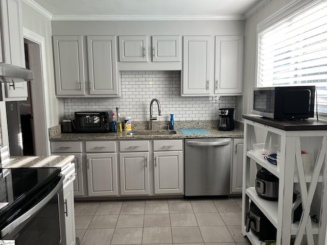 kitchen featuring tasteful backsplash, appliances with stainless steel finishes, ornamental molding, white cabinetry, and a sink