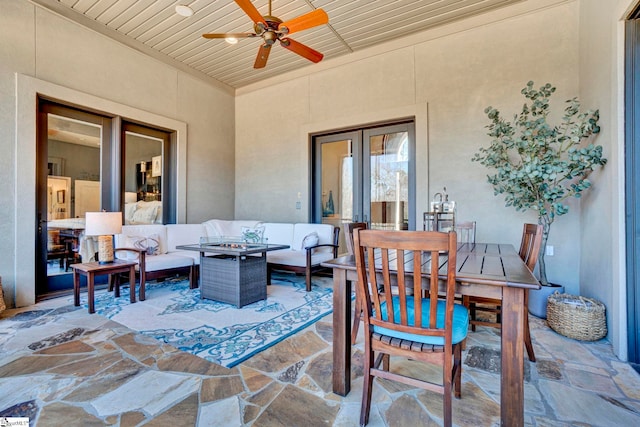 view of patio with outdoor dining area, a ceiling fan, and an outdoor living space with a fire pit