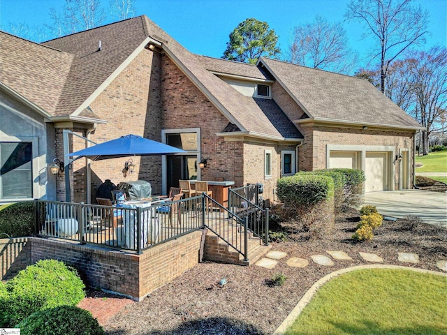 view of front facade with a shingled roof, concrete driveway, an attached garage, a wooden deck, and brick siding