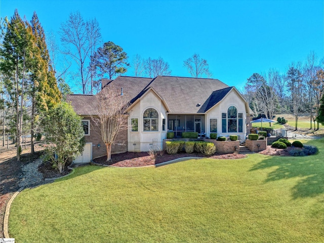 ranch-style house with a sunroom, a chimney, a front lawn, and stucco siding