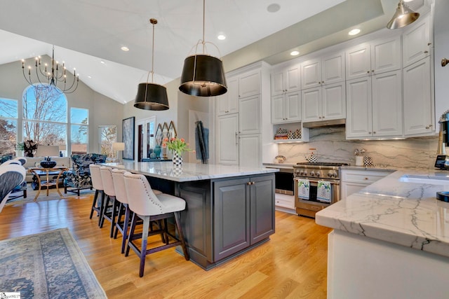 kitchen featuring pendant lighting, high end stove, white cabinets, and a kitchen island