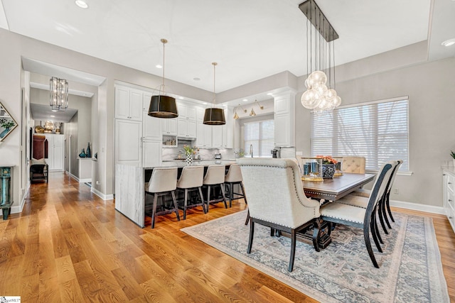 dining space featuring recessed lighting, baseboards, a chandelier, light wood-type flooring, and ornate columns