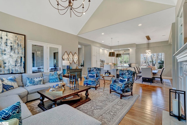 living room featuring a notable chandelier, recessed lighting, high vaulted ceiling, light wood-type flooring, and baseboards