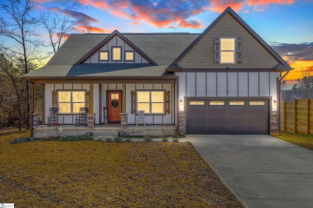 view of front of home featuring covered porch, a garage, fence, concrete driveway, and board and batten siding