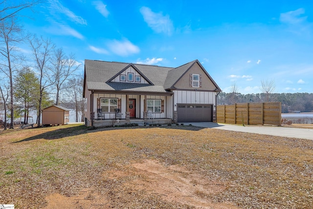 view of front of property featuring driveway, fence, a porch, board and batten siding, and a front yard