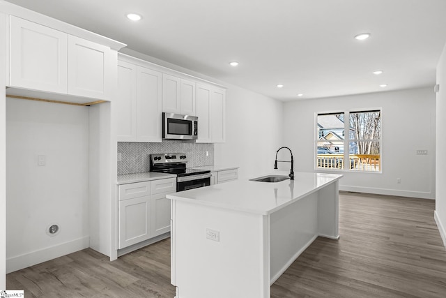 kitchen featuring a sink, white cabinets, light countertops, appliances with stainless steel finishes, and an island with sink