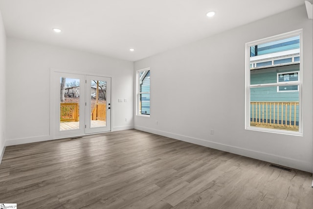 empty room featuring recessed lighting, wood finished floors, visible vents, and baseboards