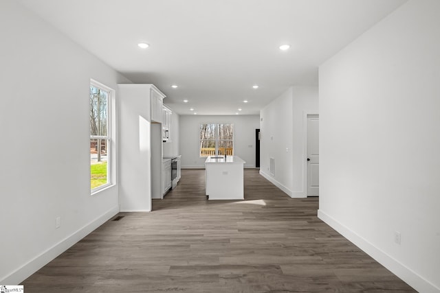 kitchen with visible vents, a kitchen island with sink, light countertops, a healthy amount of sunlight, and white cabinetry