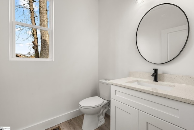 bathroom featuring toilet, wood finished floors, vanity, and baseboards