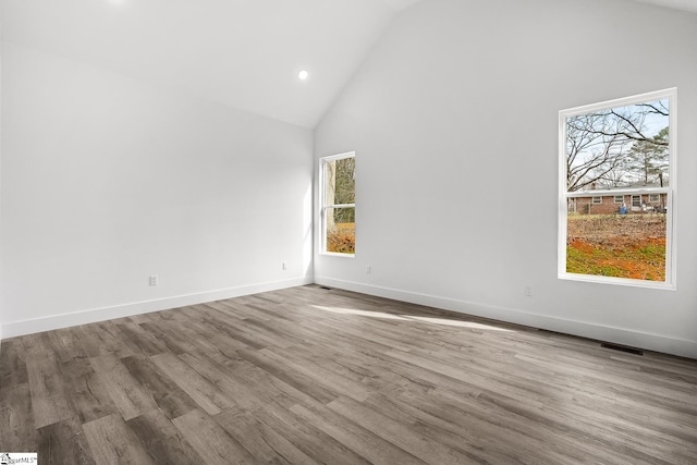 spare room with baseboards, high vaulted ceiling, wood finished floors, and recessed lighting