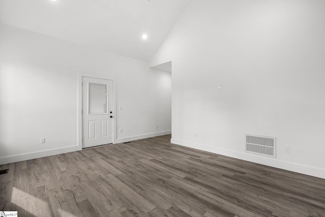 unfurnished room with high vaulted ceiling, wood finished floors, visible vents, and baseboards