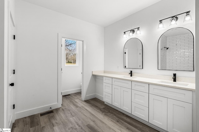 full bathroom featuring double vanity, visible vents, a sink, and wood finished floors