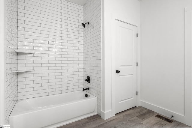 bathroom with visible vents, shower / bathing tub combination, baseboards, and wood finished floors