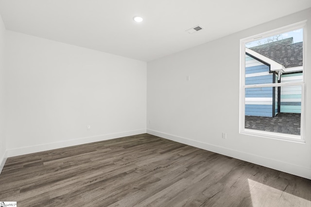 empty room with recessed lighting, dark wood finished floors, visible vents, and baseboards