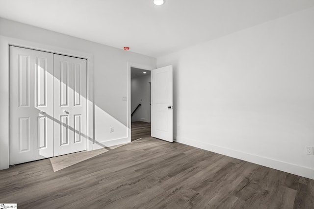 unfurnished bedroom featuring a closet, wood finished floors, and baseboards