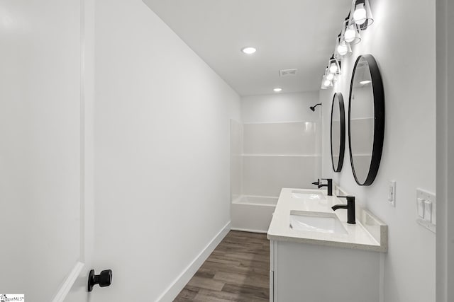 full bath with shower / washtub combination, visible vents, a sink, and wood finished floors