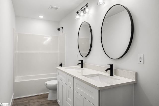 bathroom featuring wood finished floors, bathtub / shower combination, a sink, and toilet