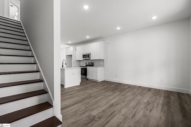 unfurnished living room with light wood-type flooring, recessed lighting, and stairs