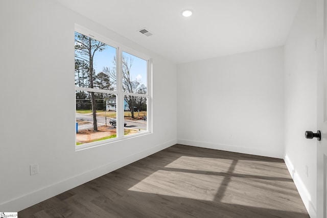 empty room with dark wood-style floors, visible vents, baseboards, and recessed lighting