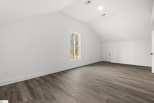 additional living space with vaulted ceiling, dark wood-type flooring, visible vents, and baseboards