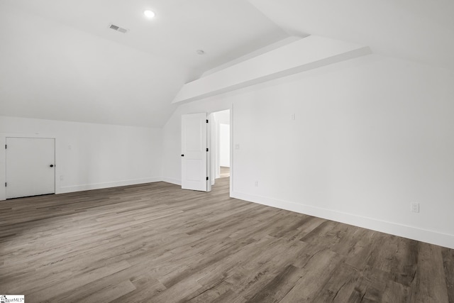 additional living space with vaulted ceiling, light wood-style flooring, visible vents, and baseboards