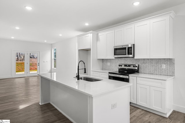 kitchen with stainless steel appliances, white cabinets, and a kitchen island with sink