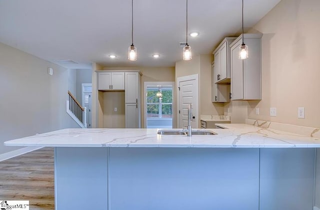 kitchen with decorative light fixtures, a sink, a peninsula, and a breakfast bar area