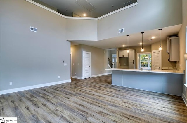 kitchen with baseboards, visible vents, a peninsula, light countertops, and pendant lighting