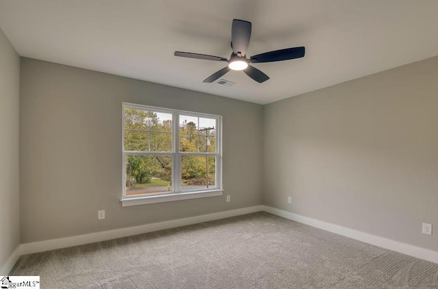 carpeted spare room with a ceiling fan, visible vents, and baseboards