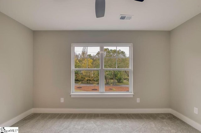 carpeted empty room featuring a ceiling fan, visible vents, and baseboards