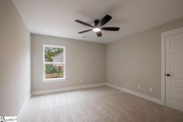 spare room with light colored carpet, ceiling fan, visible vents, and baseboards