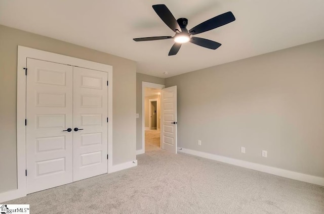 unfurnished bedroom featuring light carpet, a ceiling fan, baseboards, and a closet