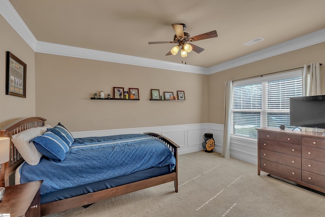 bedroom with visible vents, wainscoting, light colored carpet, ornamental molding, and a decorative wall