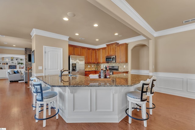 kitchen featuring appliances with stainless steel finishes, arched walkways, visible vents, and a breakfast bar area