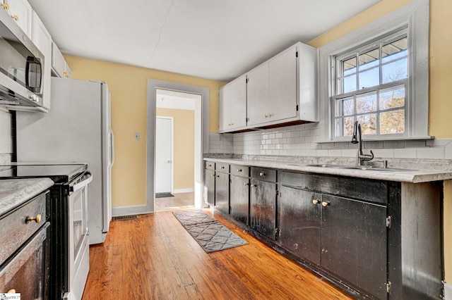 kitchen with decorative backsplash, light wood-style flooring, stainless steel appliances, light countertops, and a sink