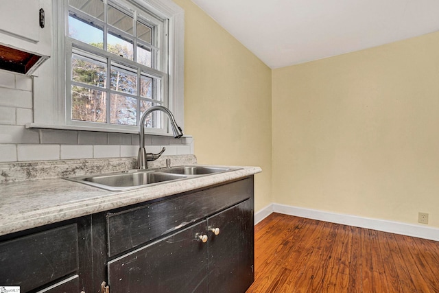 kitchen featuring light countertops, wood finished floors, a sink, and baseboards