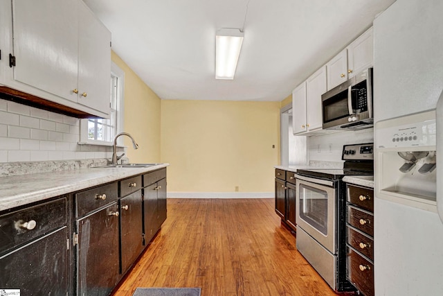 kitchen with stainless steel appliances, decorative backsplash, a sink, and white cabinets