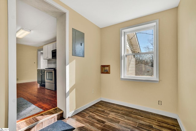 corridor with dark wood-style floors, electric panel, and baseboards