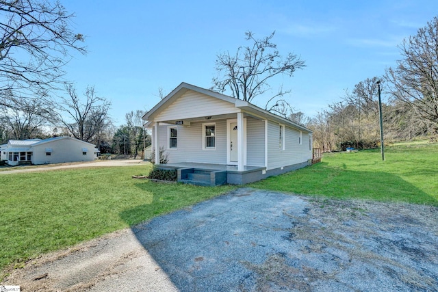 view of front of home with driveway, a porch, and a front yard