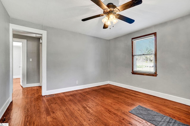 spare room featuring visible vents, wood finished floors, a ceiling fan, and baseboards