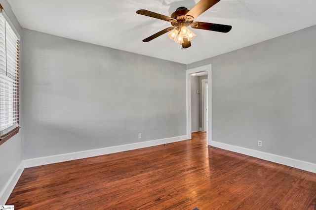 empty room with wood finished floors, a ceiling fan, and baseboards