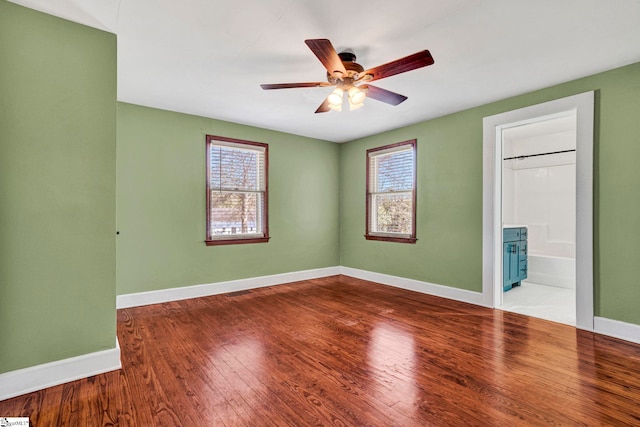 unfurnished bedroom featuring a ceiling fan, connected bathroom, baseboards, and wood finished floors