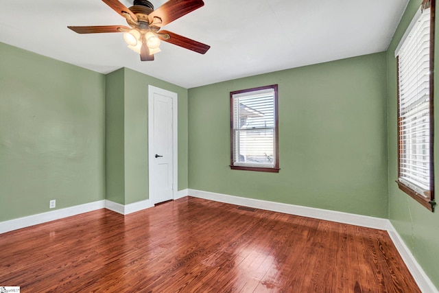 spare room with visible vents, wood finished floors, a ceiling fan, and baseboards