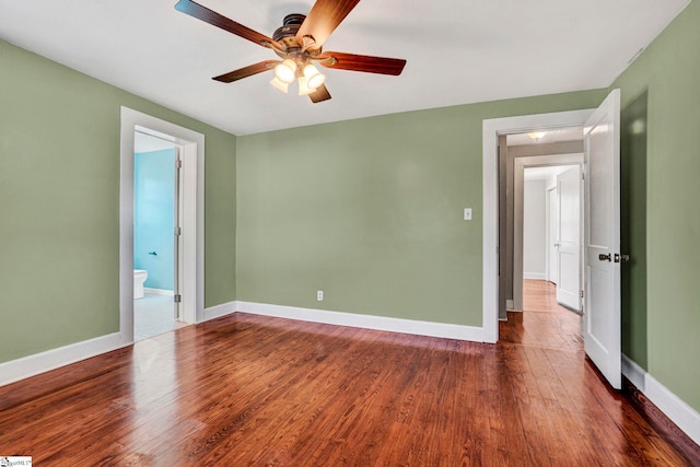 unfurnished bedroom with dark wood-type flooring, ensuite bath, baseboards, and a ceiling fan