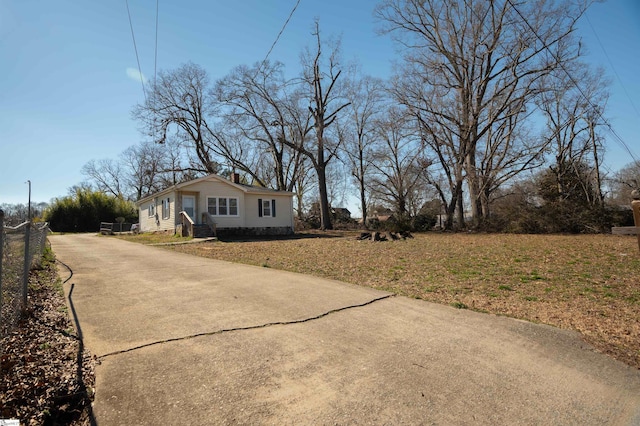 exterior space featuring driveway, fence, and a front yard