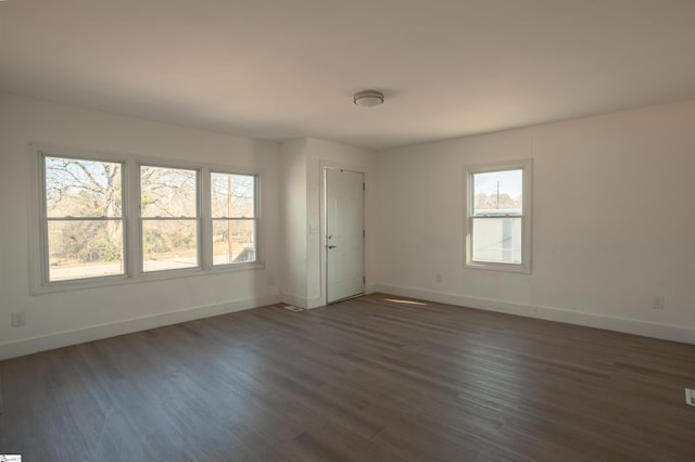 spare room with dark wood-type flooring and baseboards