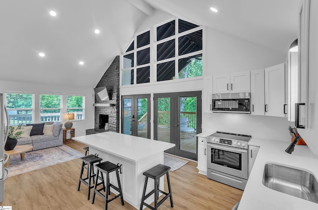 kitchen featuring a breakfast bar area, white cabinetry, open floor plan, light countertops, and appliances with stainless steel finishes