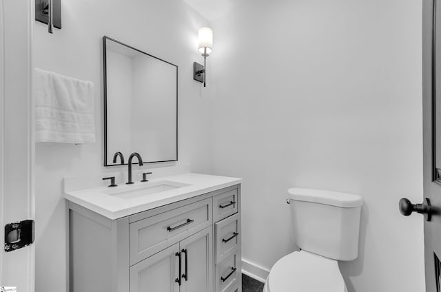 bathroom with toilet, vanity, and baseboards