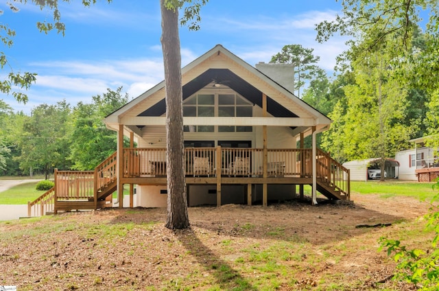 rear view of property with a detached carport, stairway, and a wooden deck