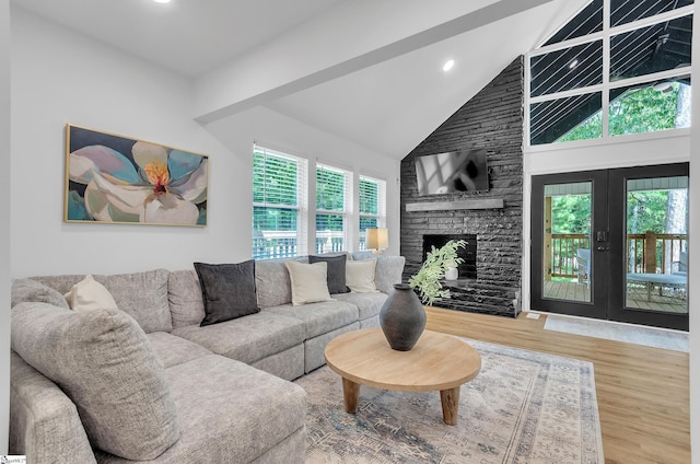 living area with high vaulted ceiling, recessed lighting, a fireplace, wood finished floors, and french doors